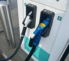 DC fast charging station installed at a gas station, showing the high-powered charging equipment with cables connected to an electric vehicle